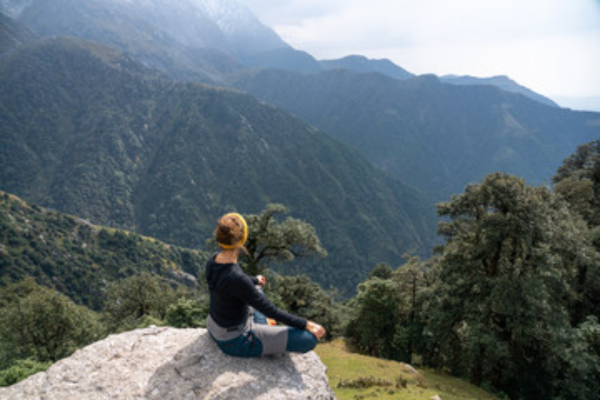 Person meditating on a rock overlooking mountains in Dharamshala