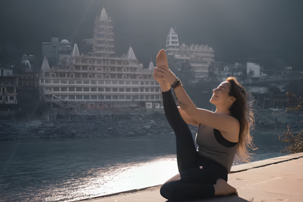 Woman practicing yoga by the Ganges in Rishikesh