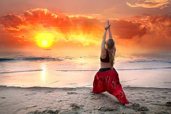 Yogi practicing yoga on a sandy beach in Kerala at sunset
