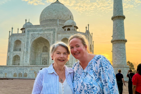 Travelers posing in front of the Taj Mahal at sunset